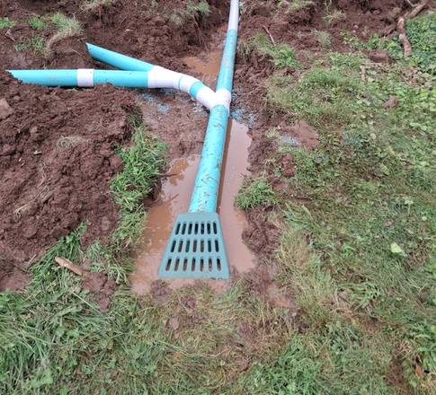 Outdoor drain lines in a trench ending at a yard grate