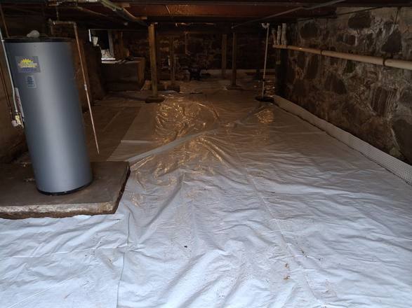 Vapor barrier laid over the floor with a drainage strip along the walls