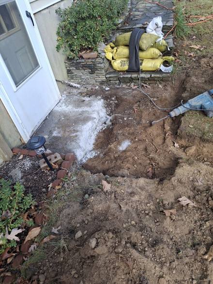 Sandbags stacked beside a basement door with the ground dug up