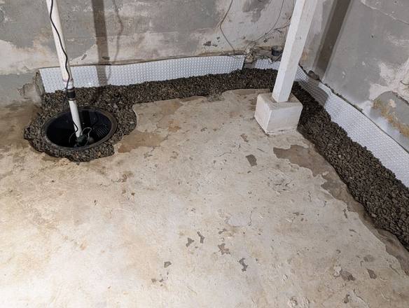 Stone-filled drain trench along the walls leading to a new sump basin