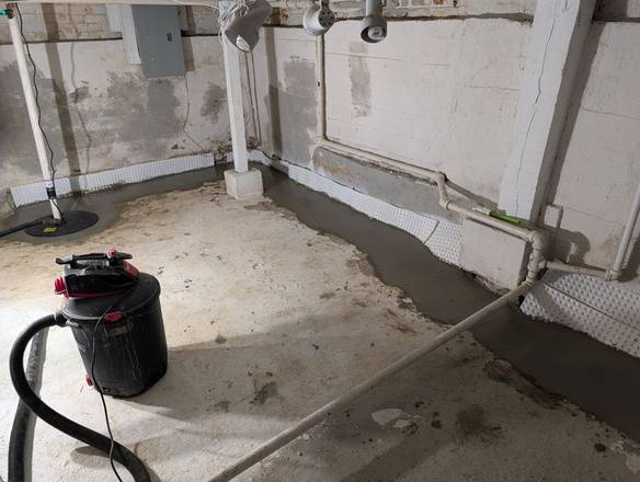 Fresh concrete along the basement walls over the finished drain