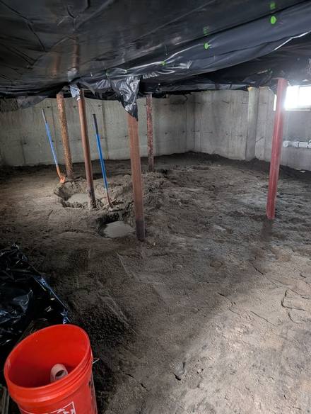 Dirt floor beneath a house with steel support posts